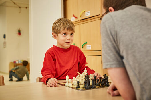 Ein Junge spielt mit einem Erzieher Schach